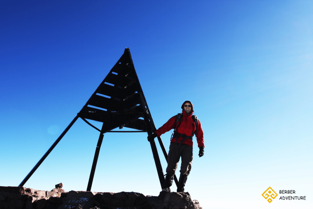 A group of hikers trekking through the Atlas Mountains with a backdrop of snow-capped peaks